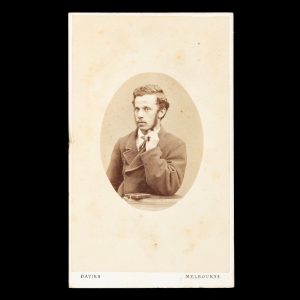 Studio portrait of a man with his elbow resting on a plinth and hand raised to his chin. Melbourne, circa 1870.