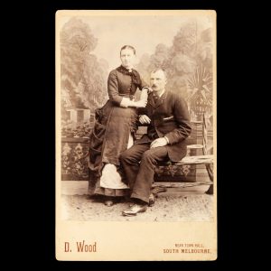 Studio portrait of a married couple posed in front of a painted backdrop of an exotic garden. South Melbourne, late 1880s.
