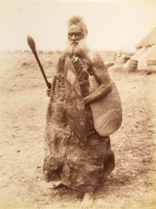 Ngarrindjeri man in skin cloak, holding weapons. Point McLeay, South Australia, 1878.