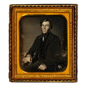 Daguerreotype of a seated gentleman wearing a silk cravat, velvet waistcoat and woollen overcoat.  Sydney, 1854-55.