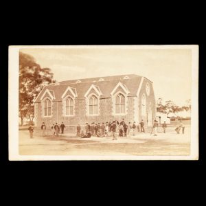 Schoolboys playing cricket and leapfrog outside the Camberwell Common School building, Melbourne, c.1867.