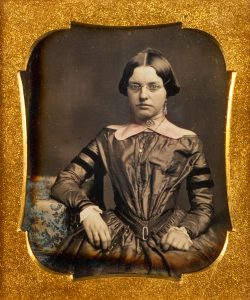Daguerreotype of a seated young woman wearing spectacles, c.1855.