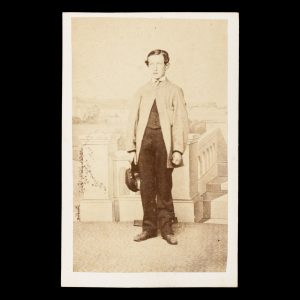 Studio portrait of a young gentleman posed before a painted backdrop with a view of Sydney Harbour. Sydney, 1866.